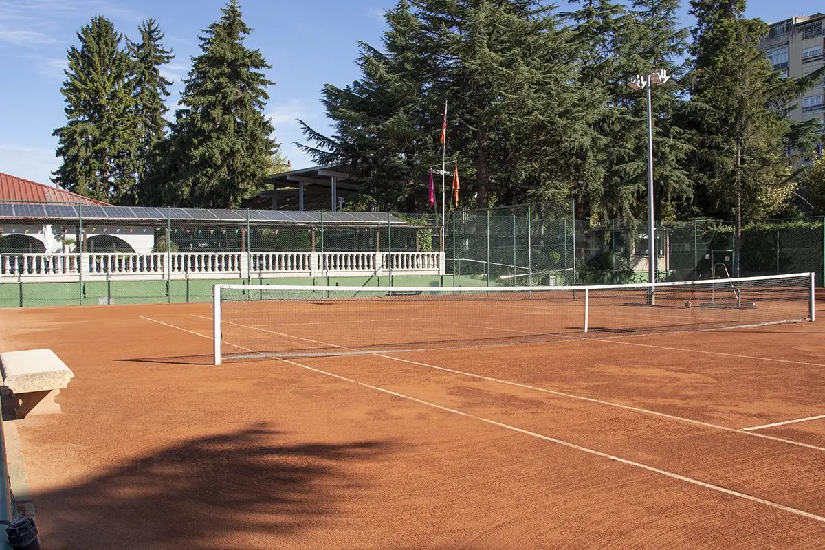 Pista de tierra batida del Club Peñalba rodeada de pinos