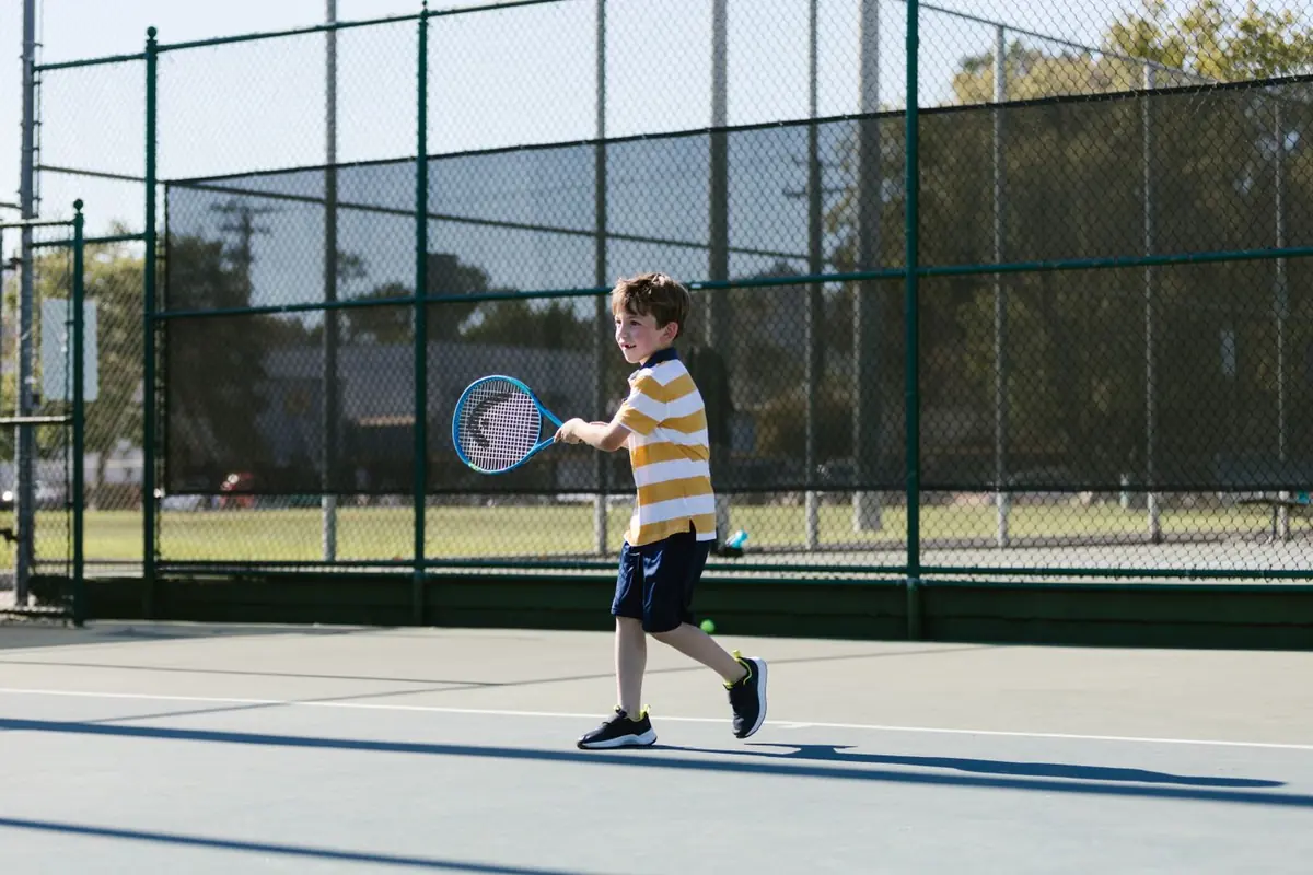 Niño golpeando de derecha en una pista de tenis