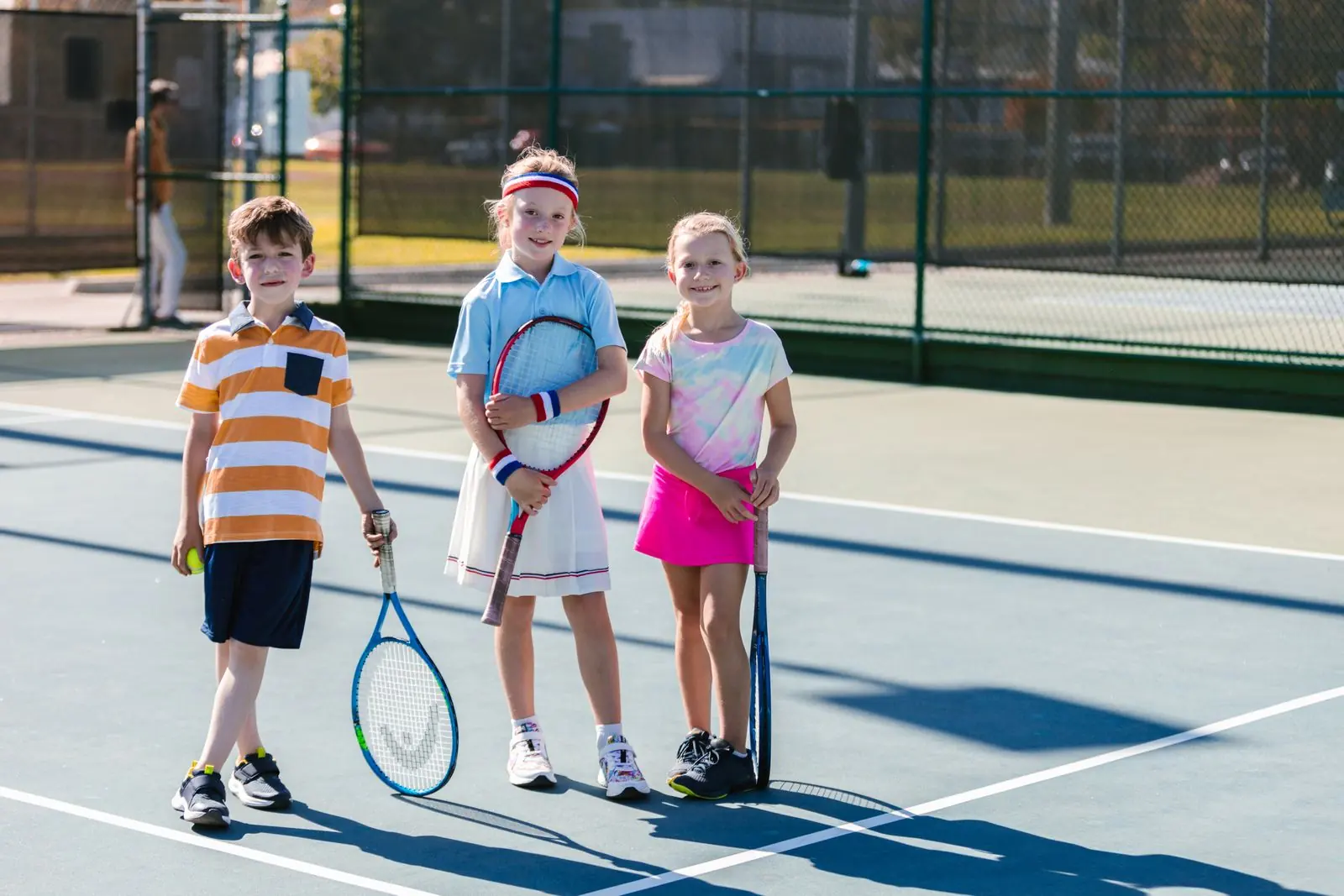Grupo de niños con raquetas caminando por la pista de tenis